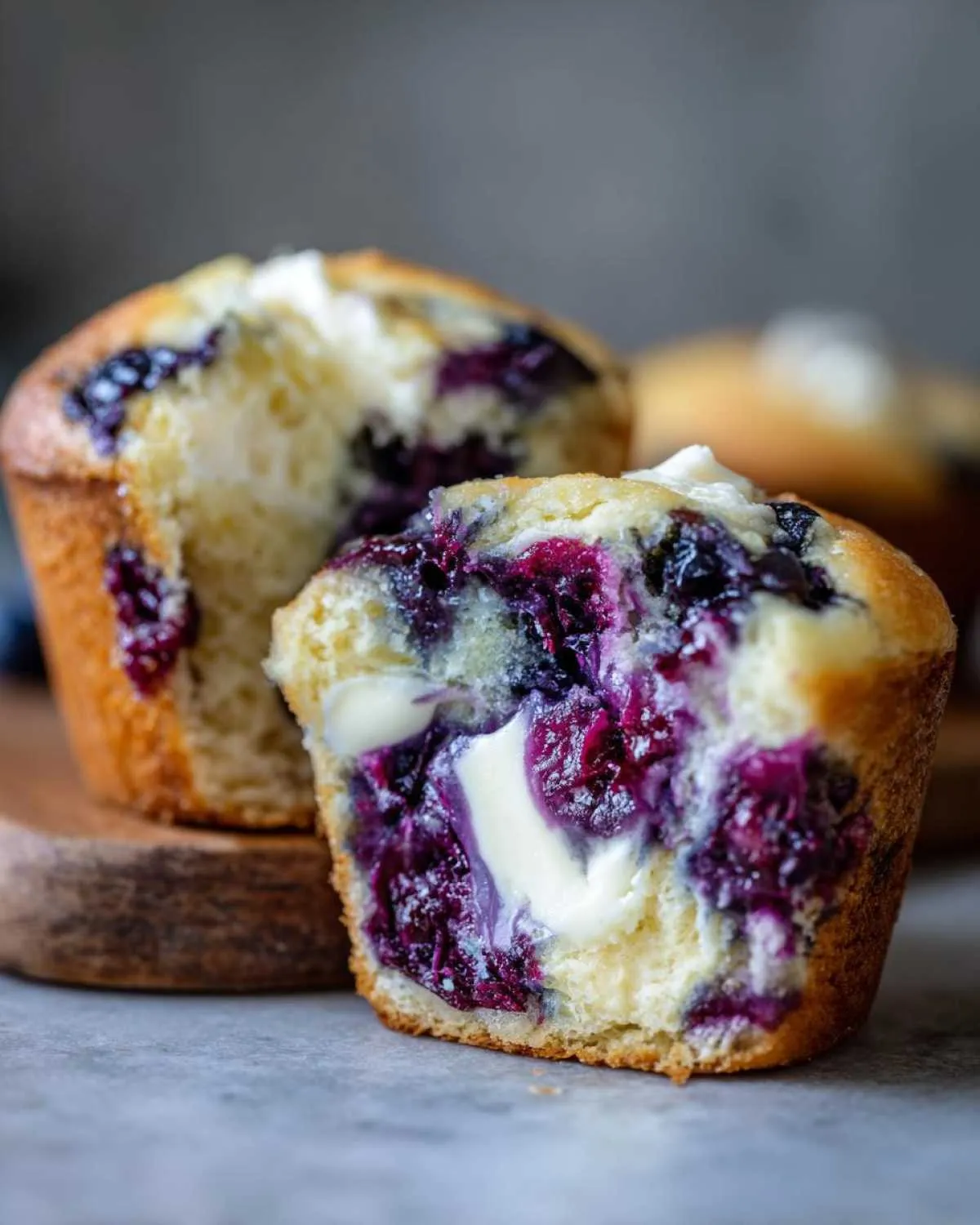 Close-up of a blueberry cream cheese muffin cut in half, showing the moist interior with bursting blueberries and a cream cheese center.