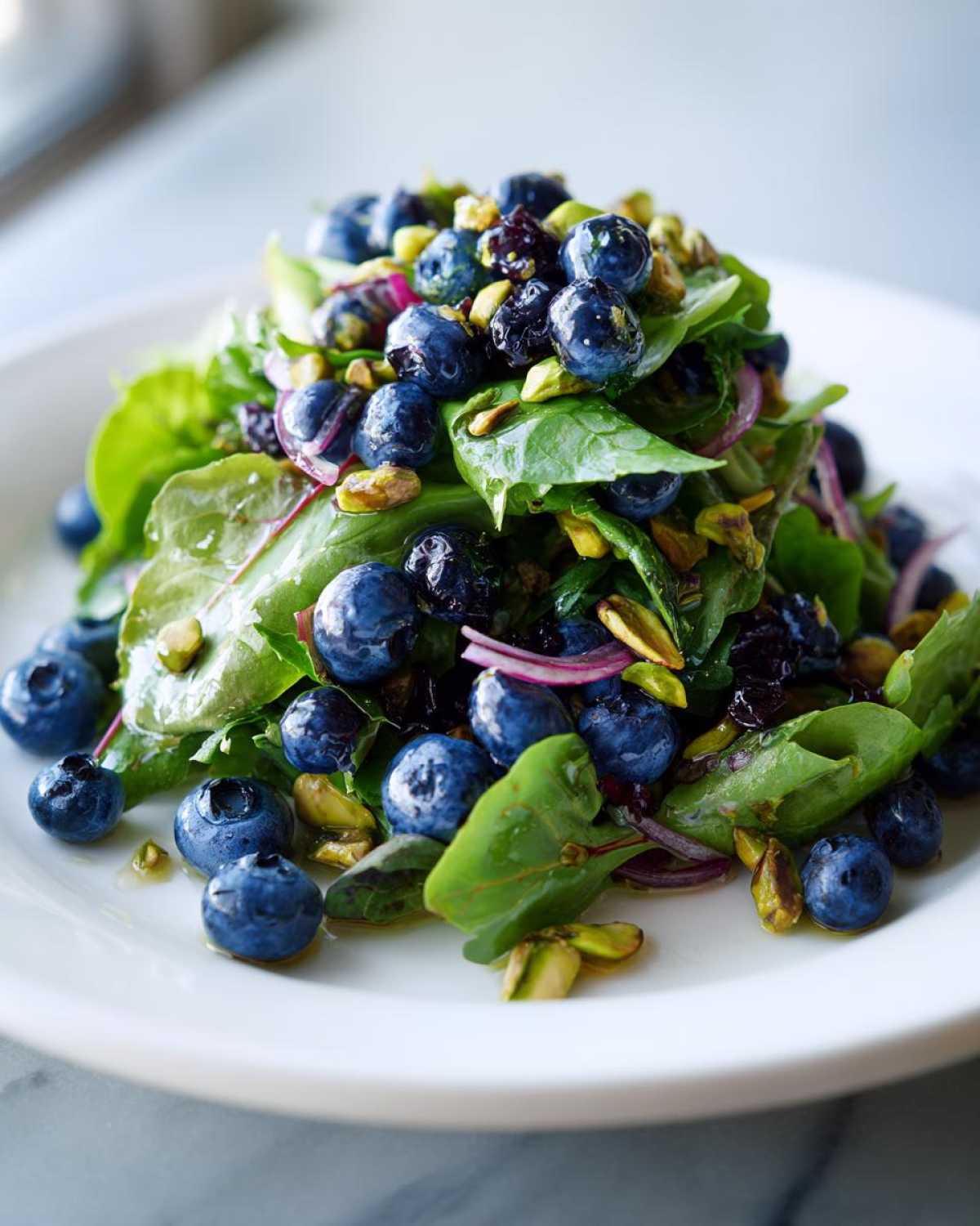 Close-up of a vibrant blueberry pistachio spring salad featuring fresh greens, whole blueberries, and chopped pistachios.