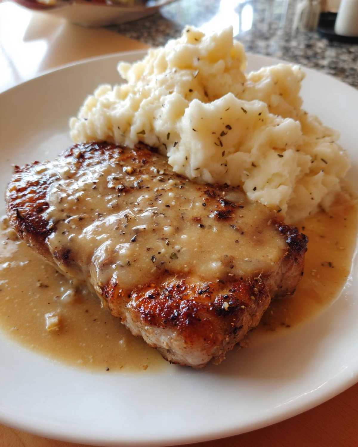 A perfectly seared piece of chicken smothered in garlic gravy served next to fluffy cheesy mashed potatoes.