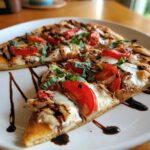 Two slices of chicken caprese flatbread topped with mozzarella, tomatoes, basil, and balsamic glaze.