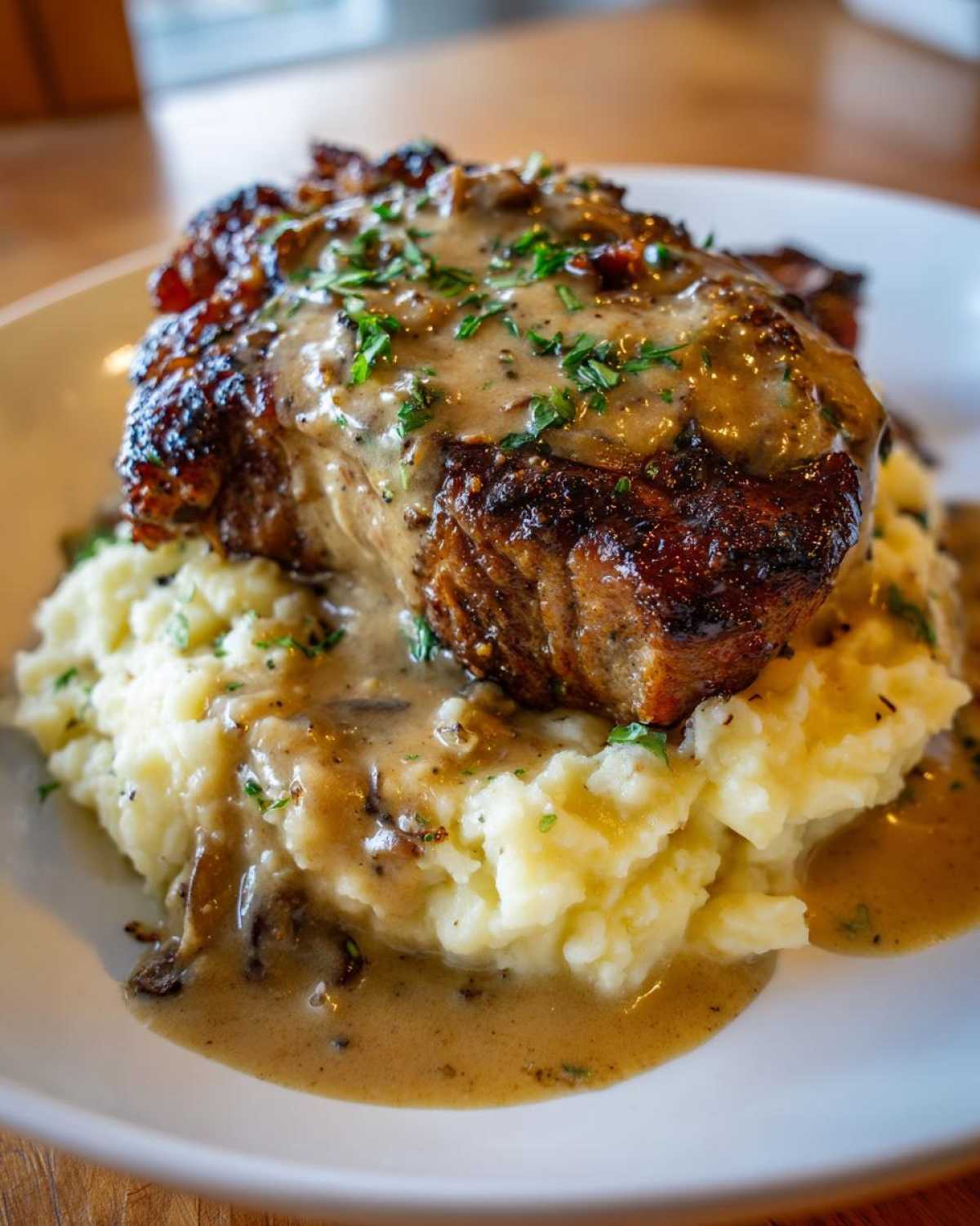 A perfectly cooked piece of chicken smothered in rich chicken and garlic gravy, served atop a mound of cheesy mashed potatoes.