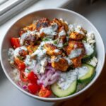 Close-up of flavorful chicken gyro bowls featuring seasoned chicken, rice, tomatoes, cucumbers, and tzatziki sauce.