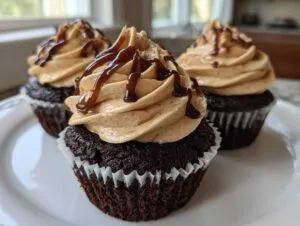 Three decadent chocolate tiramisu cupcakes topped with light brown frosting and a dark chocolate drizzle.