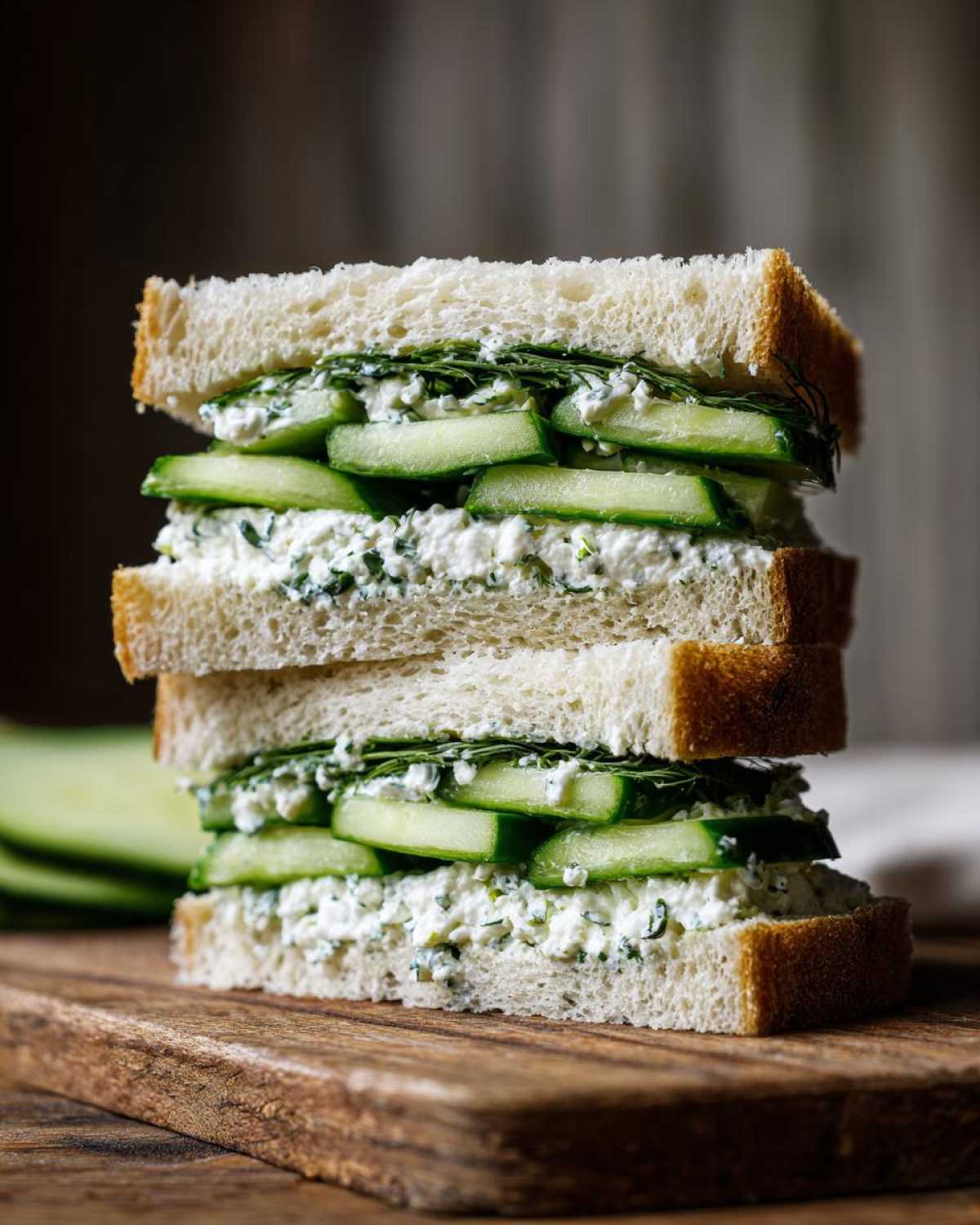 Two stacked cucumber salad sandwiches made with white bread, creamy filling, and fresh cucumber slices.
