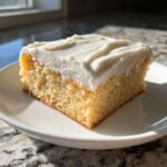A single square of thick, buttery sugar cookie bars topped with creamy white frosting.