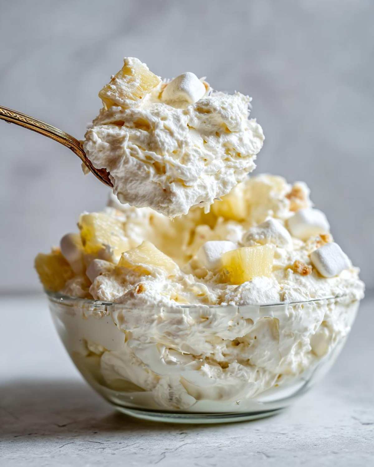 A spoonful of creamy Hawaiian pineapple coconut fluff, featuring whipped topping, pineapple chunks, and mini marshmallows.