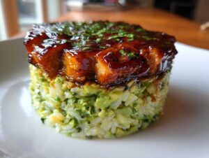 Close-up of a honey lime chicken & avocado rice stack, featuring glazed chicken on top of molded green avocado rice.