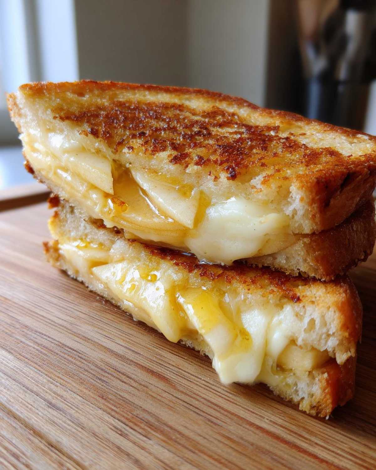 Cross-section of a grilled hot honey apple cheddar sandwich showing melted cheese and apple slices oozing out.