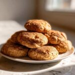 A tempting stack of moist applesauce cookies dusted heavily with cinnamon sugar, sitting on a white plate.