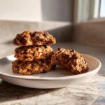 A stack of three thick, oatmeal chocolate chip breakfast cookie treats on a light plate.