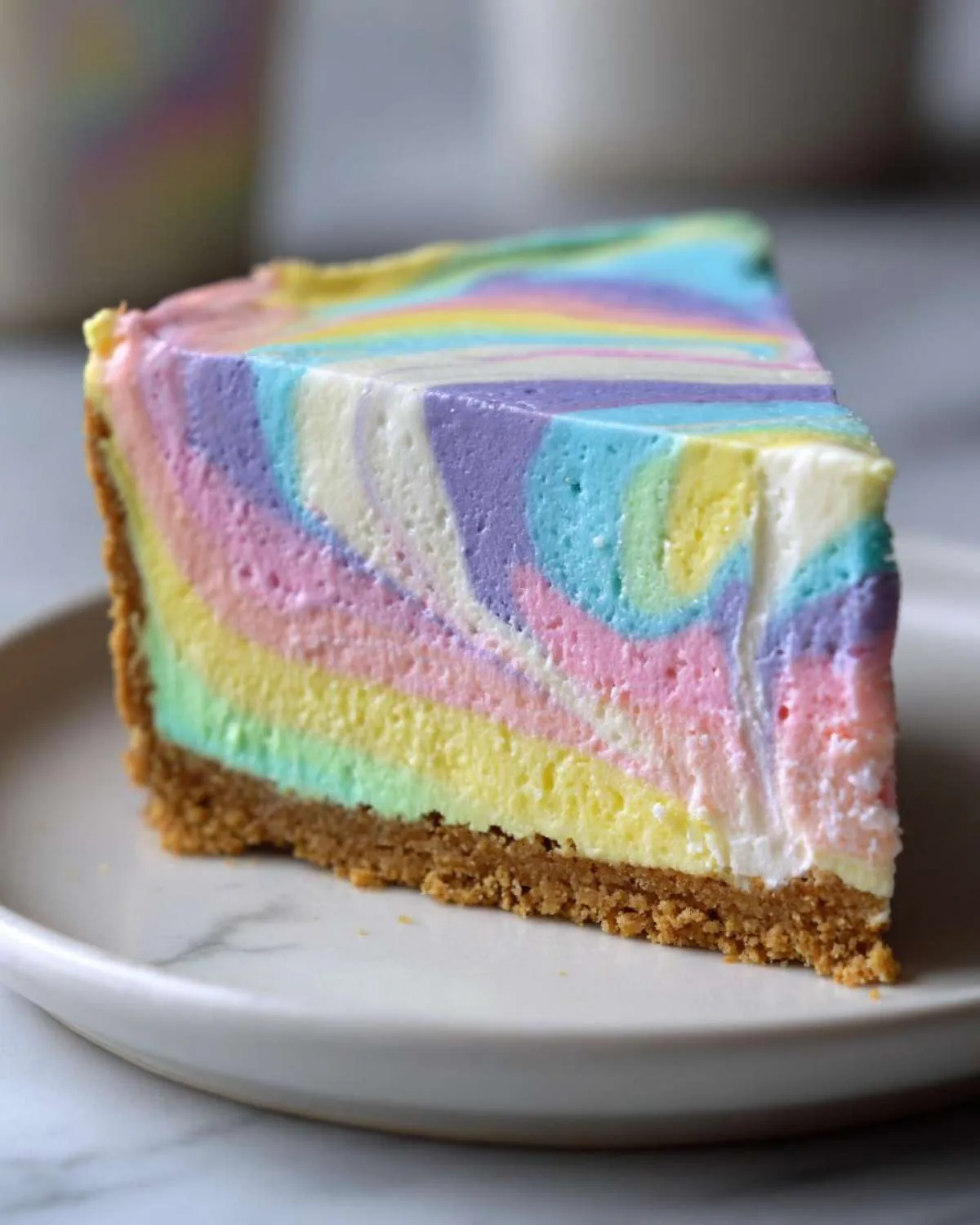 A close-up of a perfect slice of pastel easter swirl pie showing vibrant, colorful layers swirled together on a graham cracker crust.