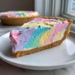 A close-up slice of pastel easter swirl pie featuring vibrant pink, purple, blue, and yellow swirls on a graham cracker crust.