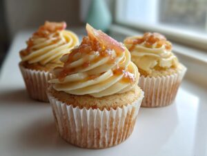 Three beautifully frosted peach bellini cupcakes topped with peach compote and glaze.