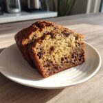 Two thick slices of chocolate chip peanut butter banana bread on a white plate.