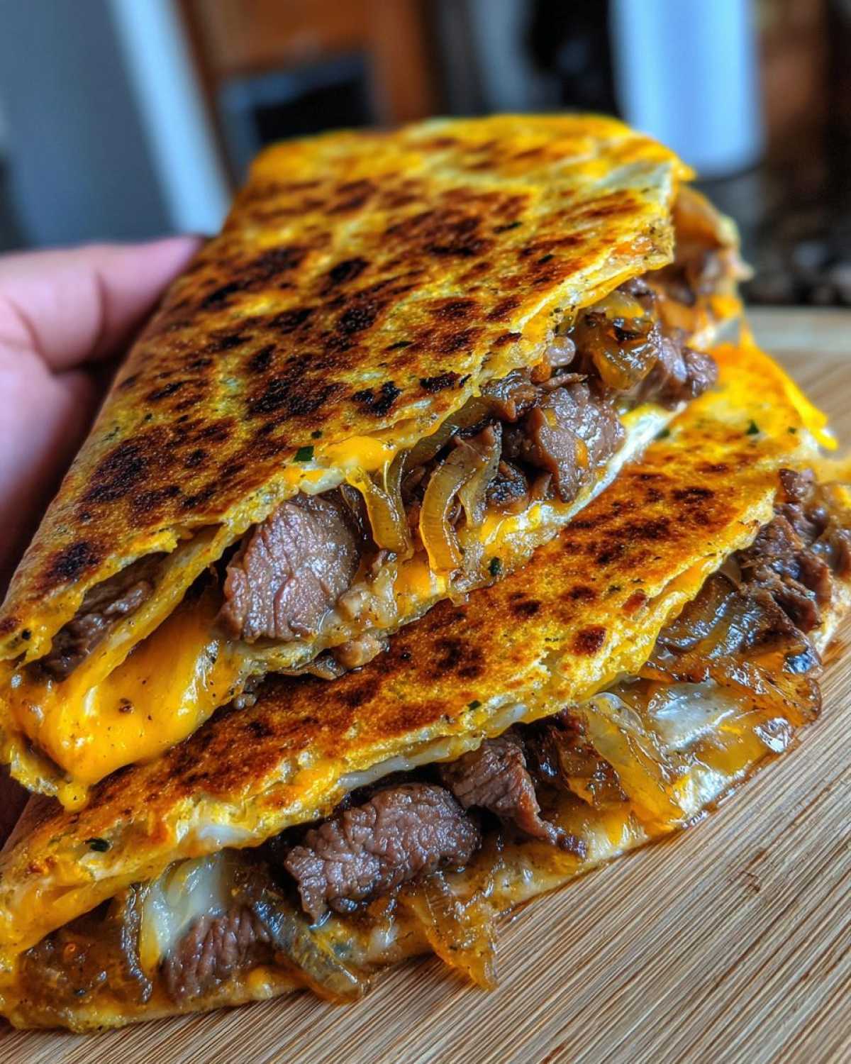 Close-up of two halves of a grilled Philly cheesesteak quesadillas showing melted cheese, steak, and caramelized onions.