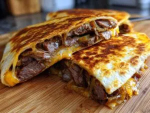 Close-up of a crispy, golden-brown philly cheesesteak quesadillas cut in half, showing steak, onions, and melted cheese.