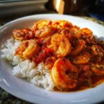 A close-up of flavorful shrimp creole served over a bed of fluffy white rice in a white bowl.