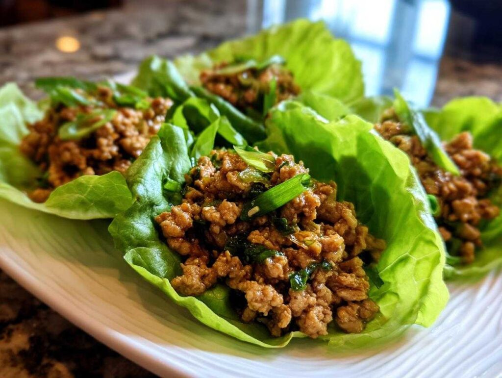 Close-up of savory chicken lettuce wraps filled with seasoned ground chicken and topped with green onions.
