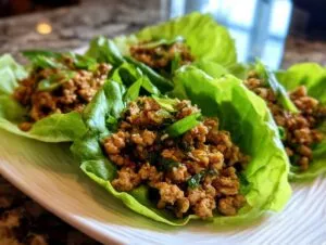 Close-up of savory chicken lettuce wraps filled with seasoned ground chicken and topped with green onions.