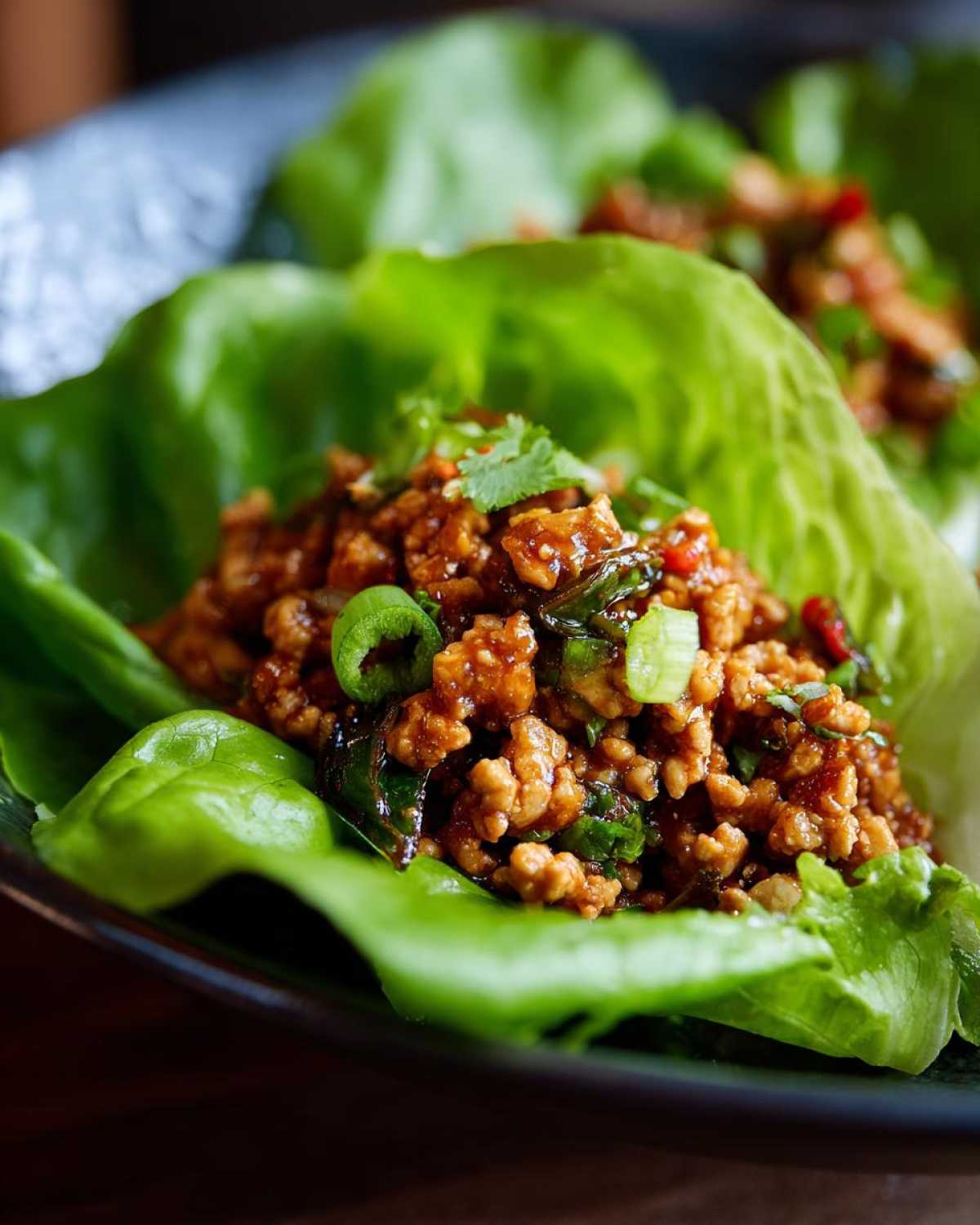 Close-up of savory ground chicken filling served in crisp lettuce cups for chicken lettuce wraps.