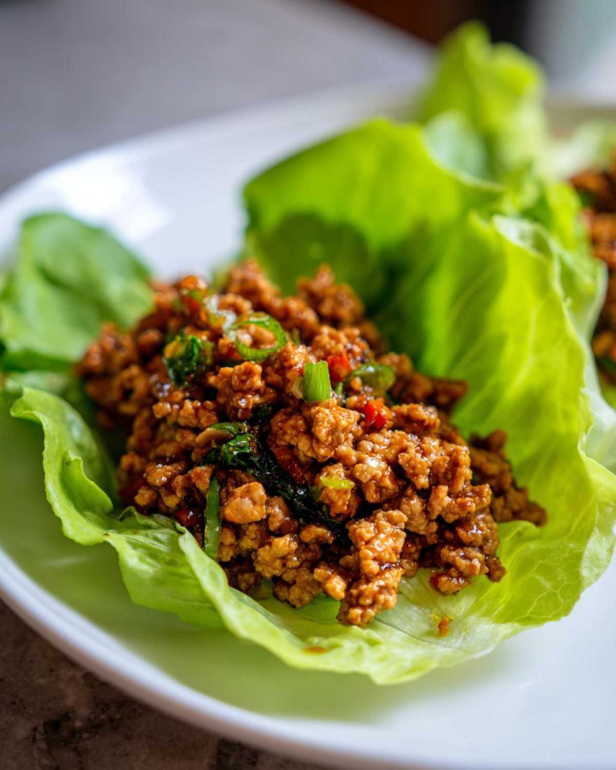 Close-up of savory ground chicken filling served in a crisp lettuce cup for chicken lettuce wraps.