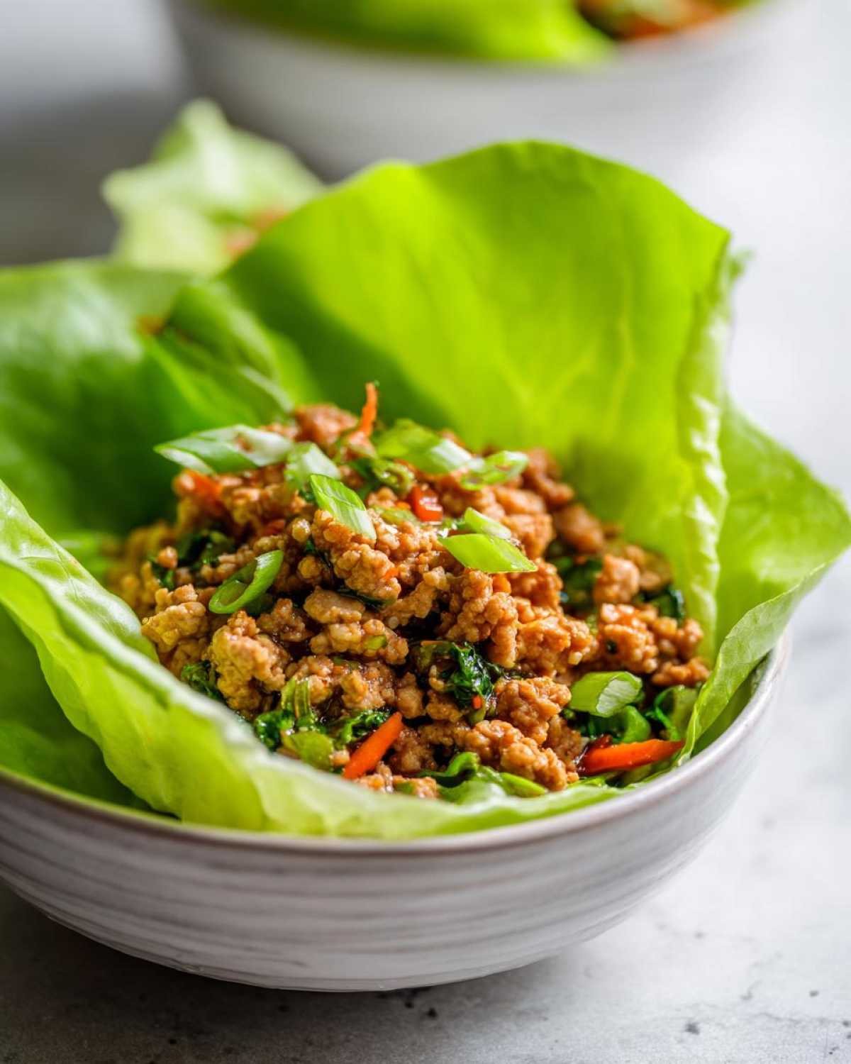 Close-up of savory ground chicken filling served in a bright green lettuce cup, ready for chicken lettuce wraps.