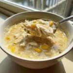 A spoonful of creamy crab and corn chowder, showing large flakes of white crab meat and bright yellow corn kernels.