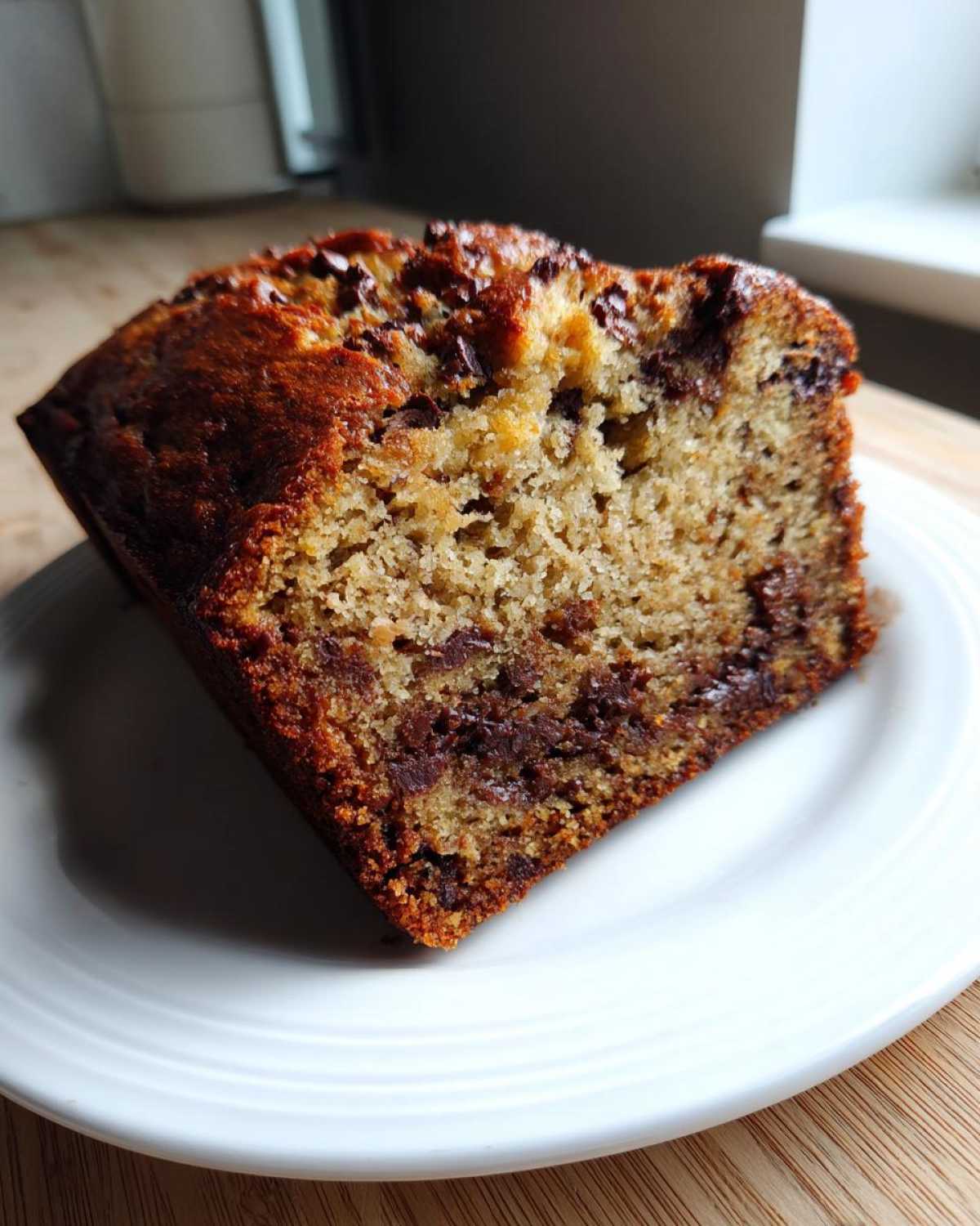 Close-up of a moist slice of peanut butter banana bread loaded with melted chocolate chips.