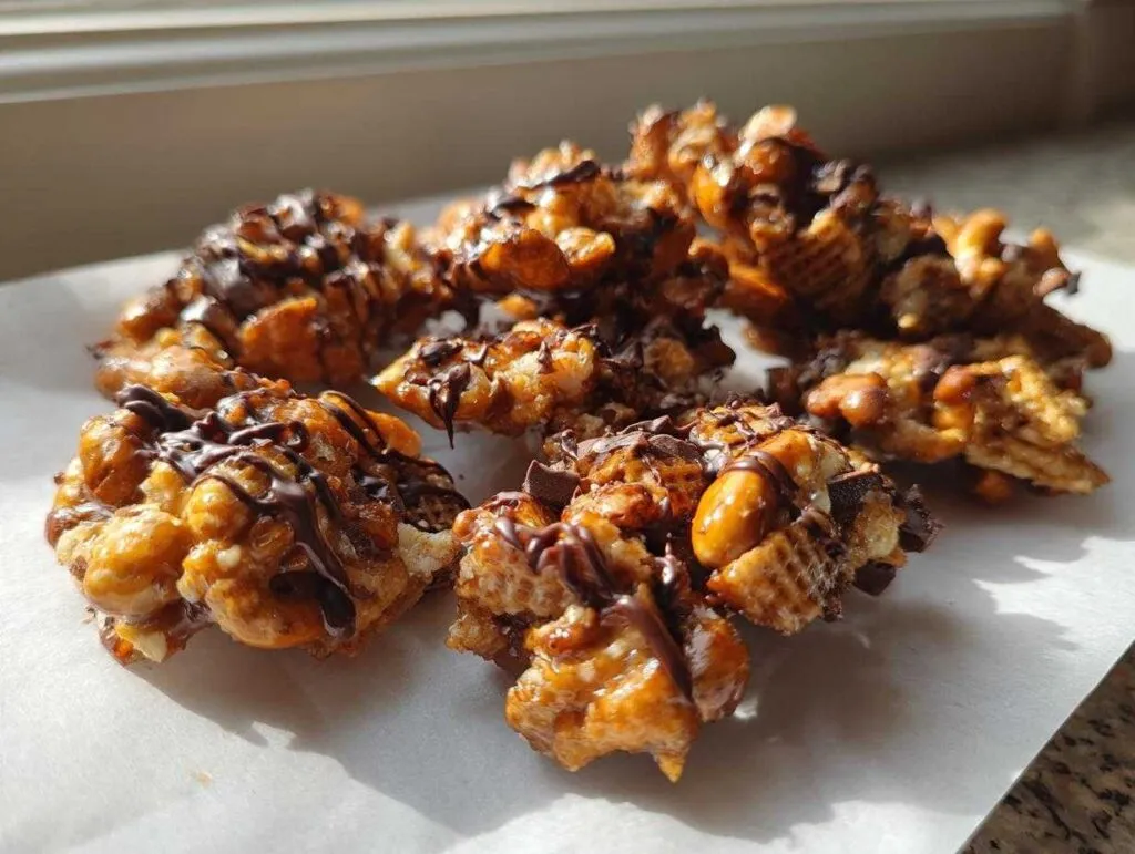 Close-up of clusters from the toffee chex mix recipe, coated in toffee and drizzled with dark chocolate.
