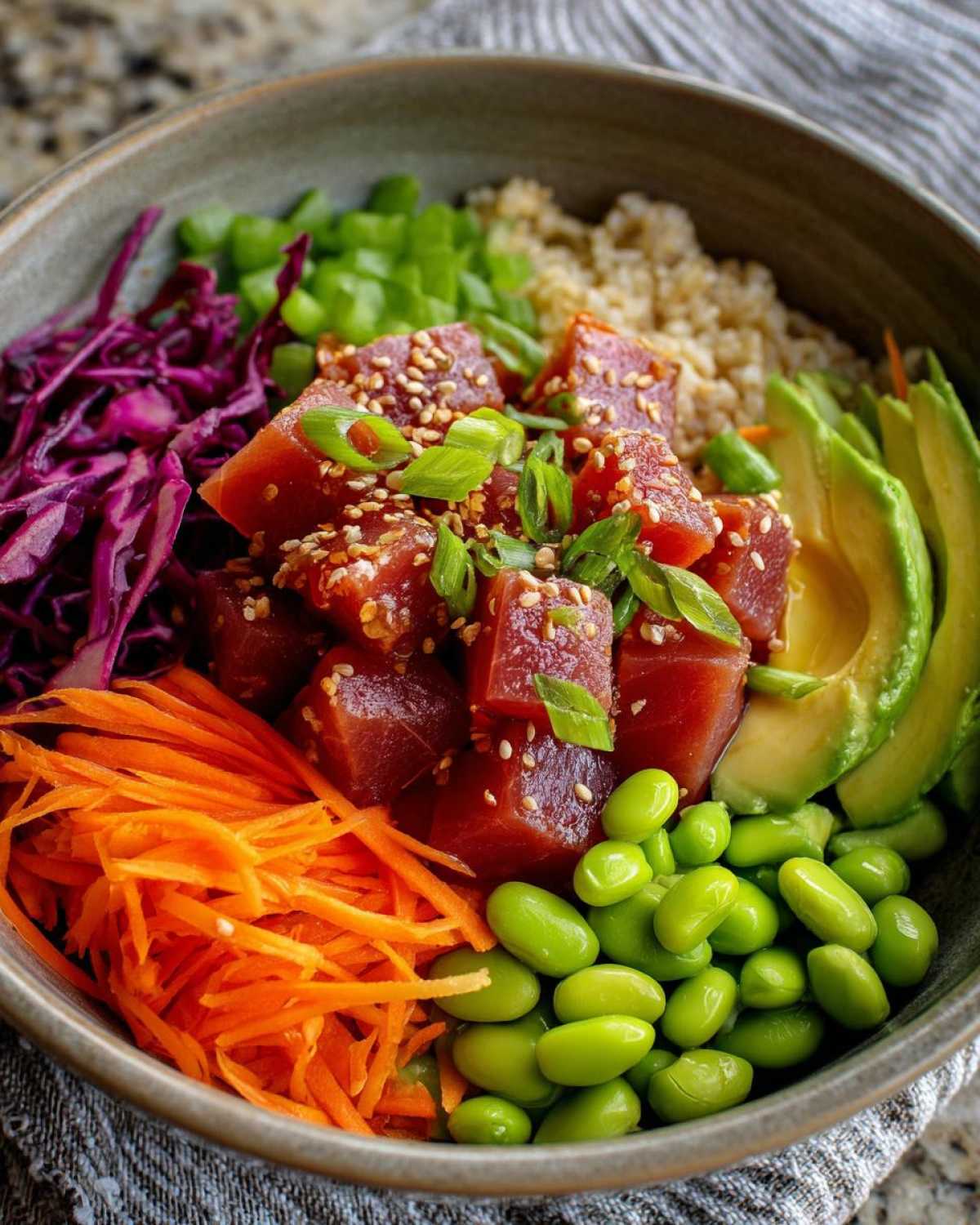 Close-up of a colorful Ahi tuna poke bowl featuring marinated tuna cubes, avocado, edamame, shredded carrots, and red cabbage.