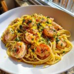 A bright white bowl filled with Garlic butter shrimp scampi tossed with spaghetti, topped generously with parsley and lemon zest.