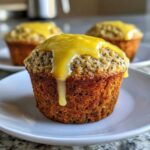 A close-up of a freshly baked lemon poppy seed muffin topped with a thick, dripping yellow lemon glaze.