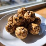A close-up stack of homemade Peanut Butter Oatmeal Energy Bites studded with mini chocolate chips on a white plate.