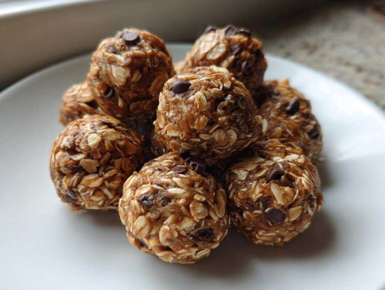 A close-up of several delicious Peanut Butter Oatmeal Energy Bites studded with mini chocolate chips, stacked on a white plate.