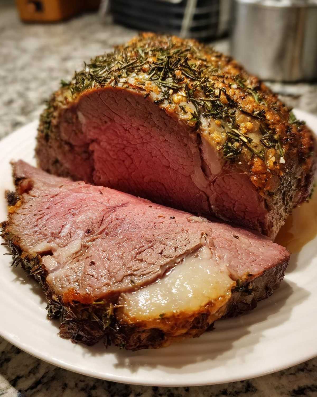 A thick slice of medium-rare roast leg of lamb, crusted with herbs, resting next to the main roast.