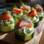 Close-up of several Smoked salmon cucumber bites topped with creamy dill spread and fresh dill sprigs.