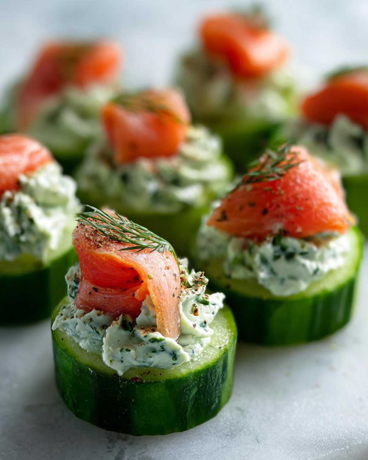 A close-up of one of the Smoked salmon cucumber bites topped with cream cheese and smoked salmon.