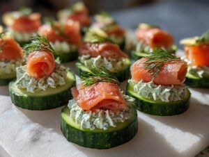 Close-up of several Smoked salmon cucumber bites topped with dill, arranged on a white marble surface.