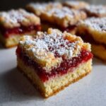 A close-up, tempting shot of a square portion of Swirled Rhubarb Bars topped with crumble and powdered sugar.