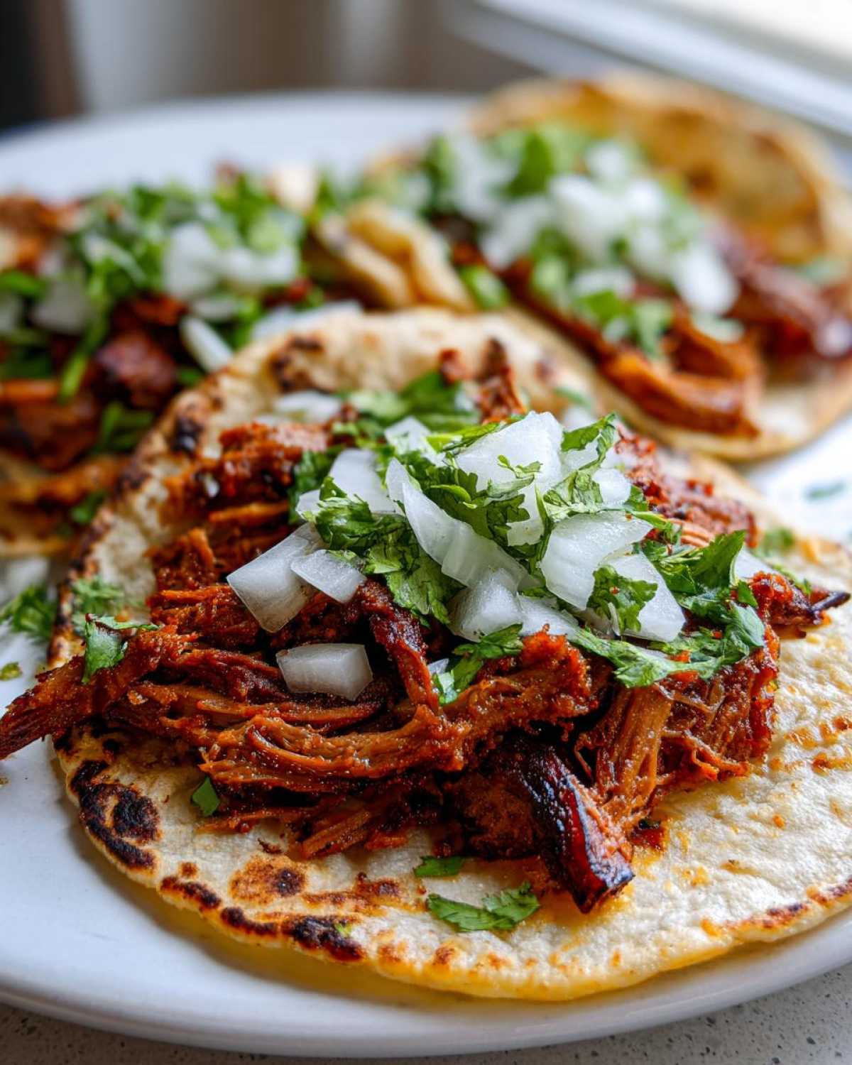 Close-up of delicious Tacos árabes served on lightly charred tortillas, topped with rich shredded meat, diced white onion, and fresh cilantro.